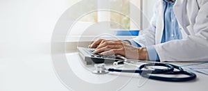 doctor typing on computer keyboard. working in hospital office. online medical consultation, communication and ehealth concept.