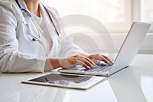 Doctor typing on her laptop computer in medical office