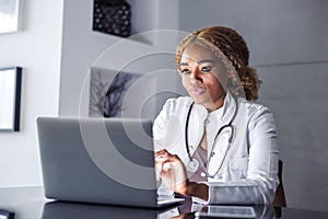 Doctor typing medical report while having online consultation with patient