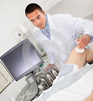 Doctor during ultrasound test of woman of knee
