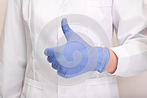 A doctor in uniform and blue nitrile gloves showing thumb up