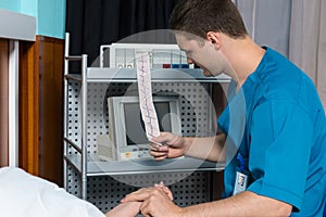 Doctor in uniform is looking at analysis of electrocardiograph e