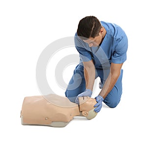 Doctor in uniform practicing first aid on mannequin against white background