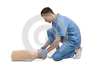 Doctor in uniform practicing first aid on mannequin against white background