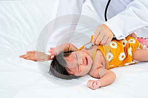 The doctor use stethoscope to check the symptom of newborn baby cry and lie on bed in room with day light