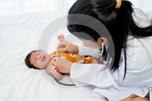 The doctor use stethoscope to check the symptom of newborn baby cry and lie on bed in room with day light