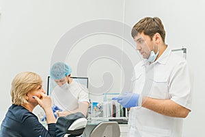 Doctor used microscope. Dentist is treating patient in modern dental office. Operation is carried out using cofferdam