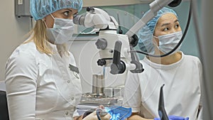 Doctor used microscope. Dentist is treating patient in modern dental office. Orthodontist work with assistant. Operation