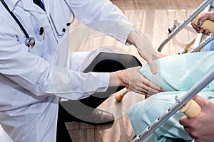 The doctor used two hands to hold the patient`s knees To check for bone injuries