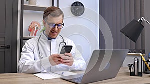 Doctor using cell mobile smartphone apps, sitting at laptop computer