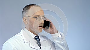 Doctor using cellphone to arrange meeting, remotely monitoring treatment process