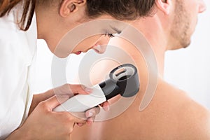 Doctor Using Dermatoscope For Skin Examination