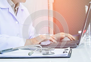 The doctor using digital labtop computer medical working information with stethoscope on desk