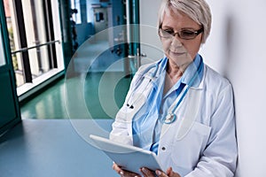 Doctor using digital tablet in corridor