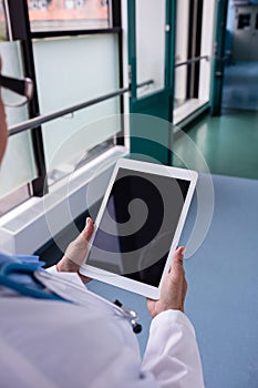 Doctor using digital tablet in corridor