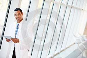 Doctor Using Digital Tablet In Corridor Of Modern Hospital