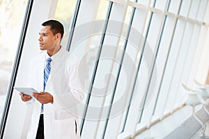 Doctor Using Digital Tablet In Corridor Of Modern Hospital