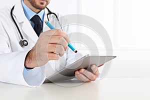 Doctor using digital tablet on desk