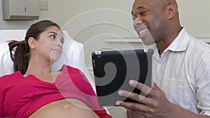 Doctor Using Digital Tablet In Examination Of Pregnant Woman