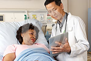 Doctor Using Digital Tablet Talking With Senior Patient