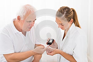 Doctor Using Glucometer On Patient`s Finger photo