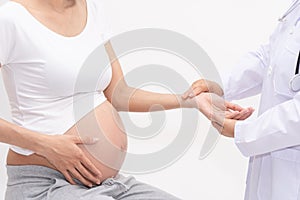 Doctor using hand and stethoscope while examining young pregnant woman in clinic,Medical exam concept