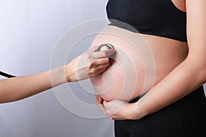 Doctor using hand and stethoscope Young pregnant woman.
