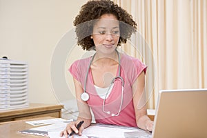 Doctor using laptop in doctor's office photo