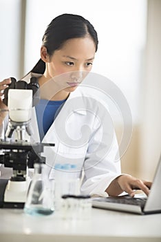 Doctor Using Laptop With Microscope At Desk