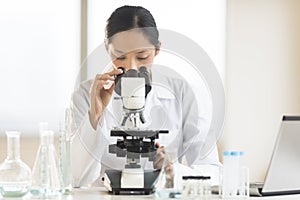 Doctor Using Microscope At Desk In Laboratory