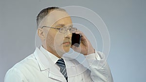 Doctor using mobile phone, dialing number, calling patient to arrange meeting