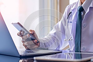 Doctor using mobile smart phone with laptop computer