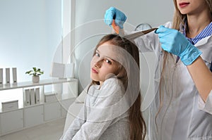 Doctor using nit comb on girl`s hair in clinic. Anti lice