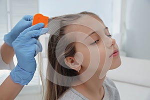 Doctor using nit comb on girl`s hair in clinic. Anti lice photo