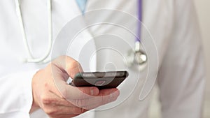 A doctor is using a smartphone, close up.