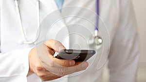 A doctor is using a smartphone, close up.