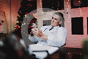 Doctor Using Smartphone in Office on New Year Eve.