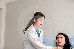 Doctor using stethoscope checking to asian woman patient for listening heart rate on sickbed in hospital room