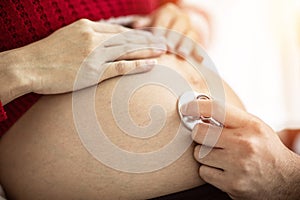 Doctor using stethoscope for examining and diagnosis pregnant woman in Pregnancy hospital or clinic