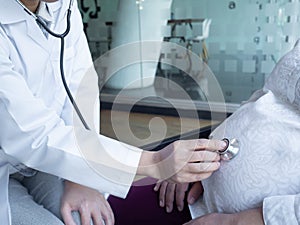 A doctor using stethoscope while examining a pregnant woman in a clinic