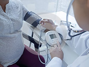 A doctor using stethoscope while examining a pregnant woman in a clinic