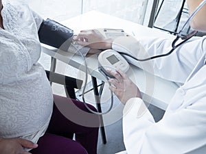 A doctor using stethoscope while examining a pregnant woman in a clinic