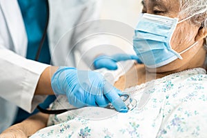 Doctor using stethoscope to checking Asian senior or elderly old lady woman patient wearing a face mask in hospital for protect