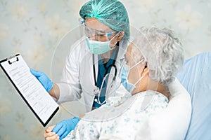 Doctor using stethoscope to checking Asian senior or elderly old lady woman patient wearing a face mask in hospital for protect