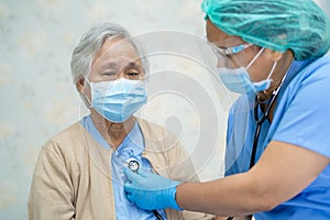 Doctor using stethoscope to checking Asian senior or elderly old lady woman patient wearing a face mask in hospital for protect