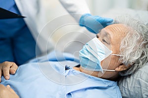 Doctor using stethoscope to checking Asian senior or elderly old lady woman patient wearing a face mask in hospital for protect