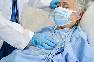 Doctor using stethoscope to checking Asian senior or elderly old lady woman patient wearing a face mask in hospital for protect