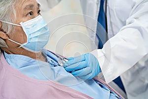 Doctor using stethoscope to checking Asian senior or elderly old lady woman patient wearing a face mask in hospital for protect