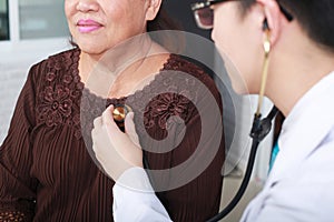 Doctor using stethoscope to exam woman patient heart.