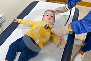 Doctor using stethoscope to listen breathing of a baby boy at the routine checkup at the doctors office in the hospital